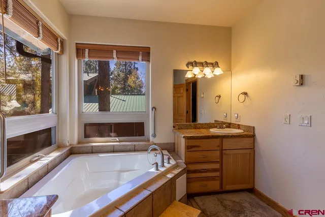 a spacious bathroom with a tub a double vanity sink and a mirror