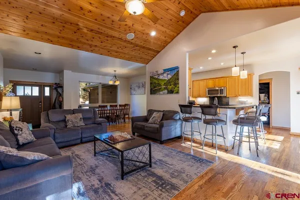 a living room with furniture kitchen view and a wooden floor