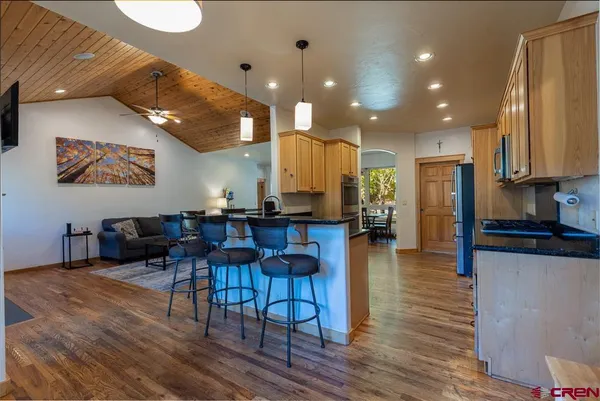 a living room with furniture a wooden floor and kitchen view