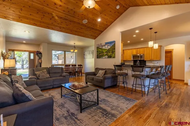 a living room with furniture a wooden floor and kitchen view