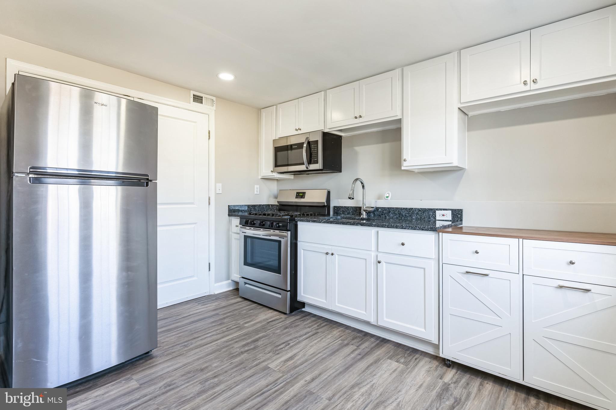 815 Fifth Avenue Baltimore, MD 21227 - Photo 2 of 17 a kitchen with granite countertop white cabinets and stainless steel appliances