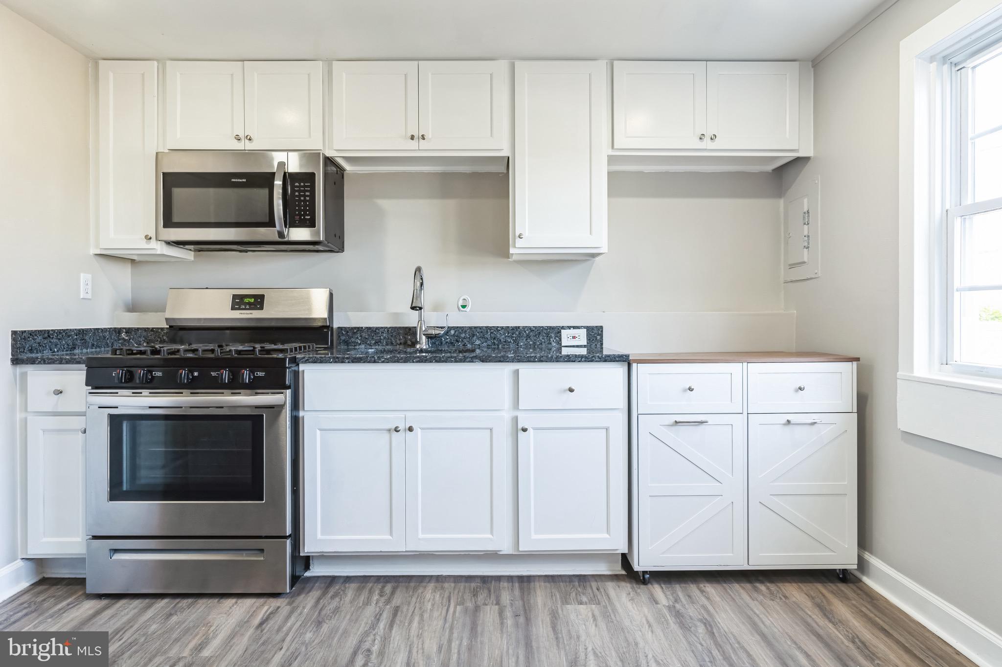 815 Fifth Avenue Baltimore, MD 21227 - Photo 3 of 17 a kitchen with granite countertop white cabinets and stainless steel appliances