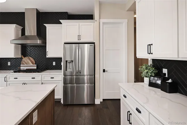 a kitchen with a refrigerator white stove top oven and cabinets