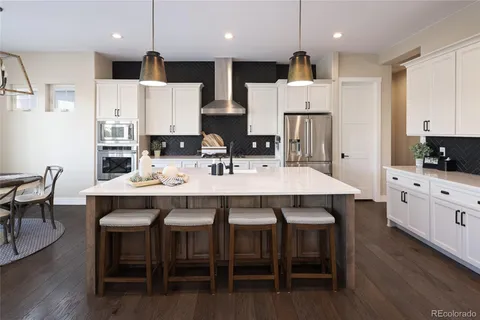 a kitchen with stainless steel appliances kitchen island granite countertop a table chairs sink and cabinets
