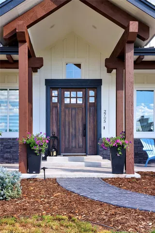 a view of a house with large windows and flower plants