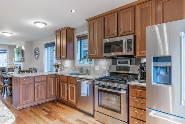 a kitchen with stainless steel appliances granite countertop a stove a sink dishwasher a refrigerator and cabinets with wooden floor