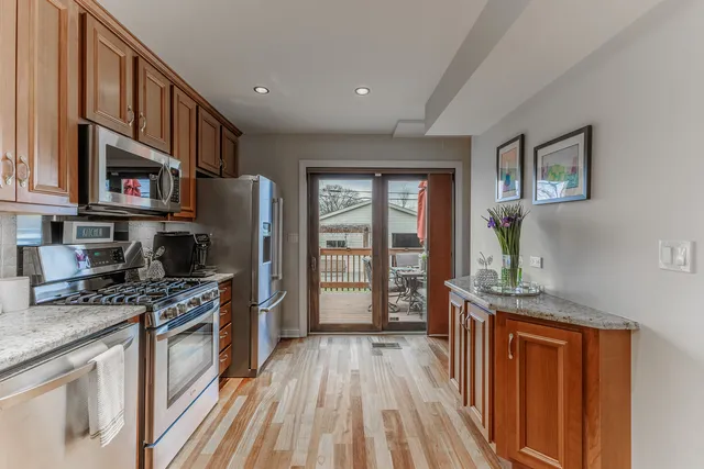 a kitchen with stainless steel appliances granite countertop a lot of cabinets and wooden floor