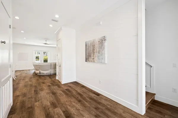 a large white kitchen with a stove a sink a refrigerator and white cabinets with wooden floor