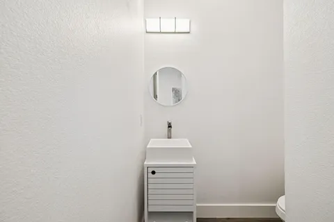 a view of a white house with a yard and lawn chairs under an umbrella