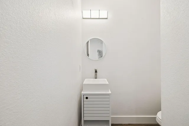 a view of a white house with a yard and lawn chairs under an umbrella
