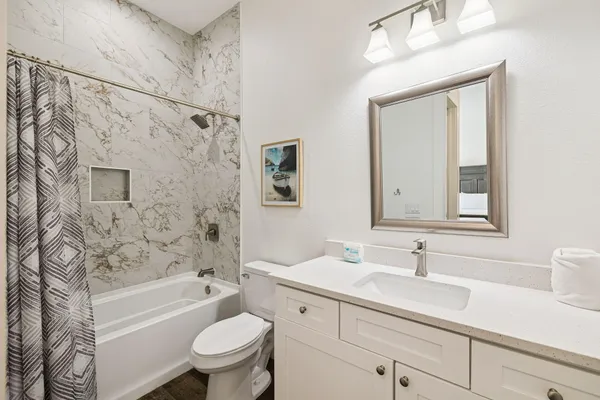 a bathroom with a granite countertop sink toilet tub and shower