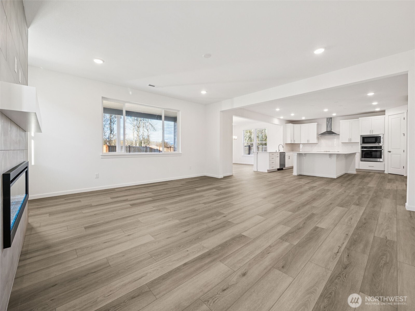 1132 Tanner Avenue, Unit 111 Buckley, WA 98321 - Photo 9 of 17 a view of kitchen and empty room with wooden floor and windows