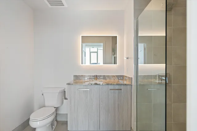 a bathroom with a granite countertop sink a toilet and a mirror
