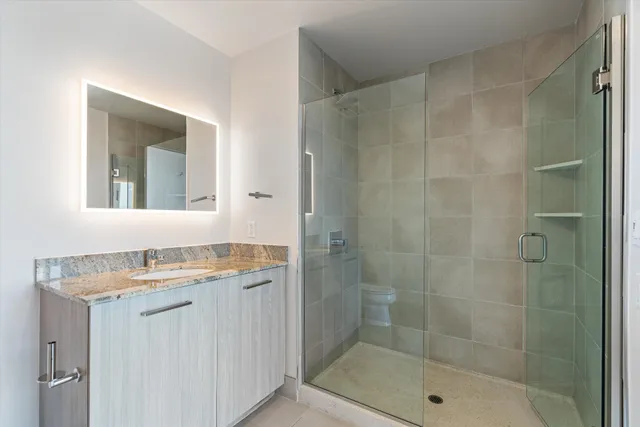 a bathroom with a granite countertop sink a mirror and shower