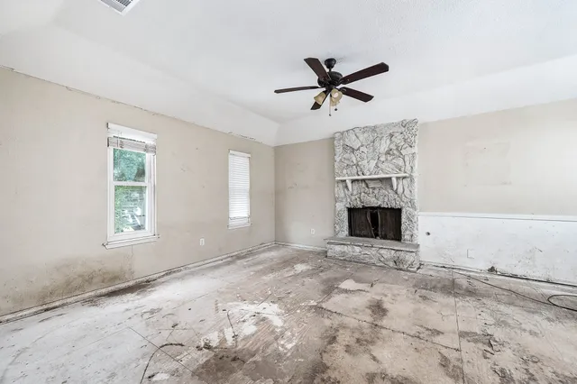 a view of a livingroom with a fireplace a ceiling fan and windows