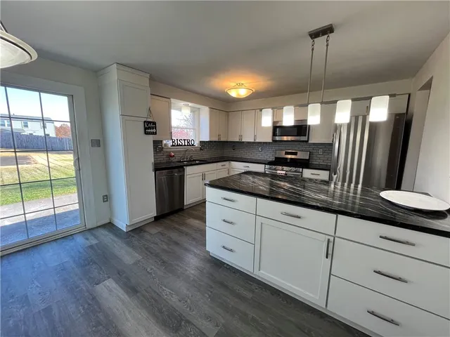 a kitchen with stainless steel appliances granite countertop a stove a sink and a refrigerator with wooden floors