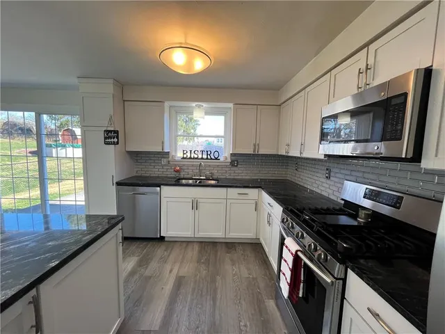 a kitchen with stainless steel appliances granite countertop a stove a sink and a microwave