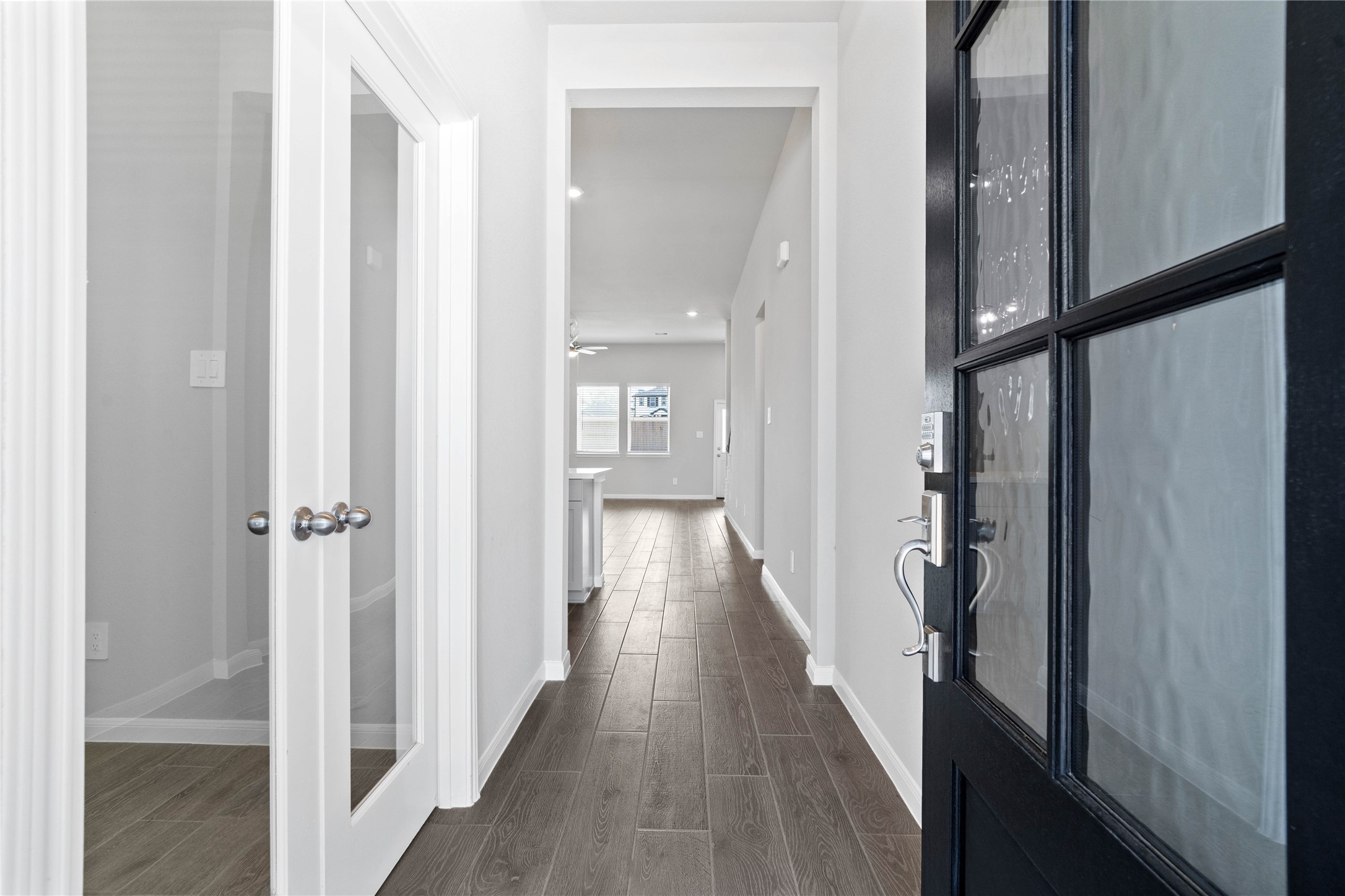 19657 Montgomery Rdg Way Montgomery, TX 77316 - Photo 6 of 49 This entryway features a modern, open-concept design. The long, bright corridor utilizes a neutral color palette, recessed lighting, and wood-look tile flooring to lead the eye toward the home's main living area.