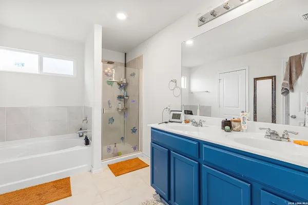a bathroom with a tub sink double vanity granite tub shower and mirror