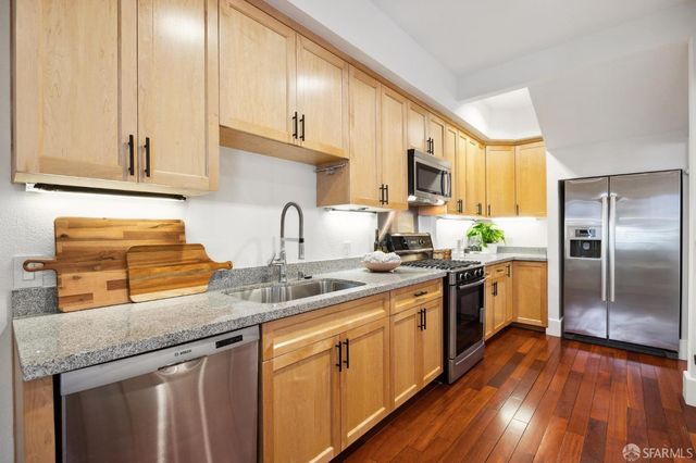 a kitchen with stainless steel appliances granite countertop a sink a stove cabinets and wooden floor
