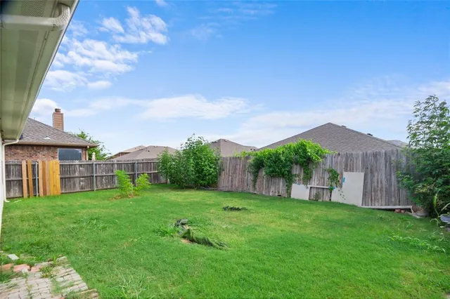 a view of a house with a yard potted plants and wooden fence