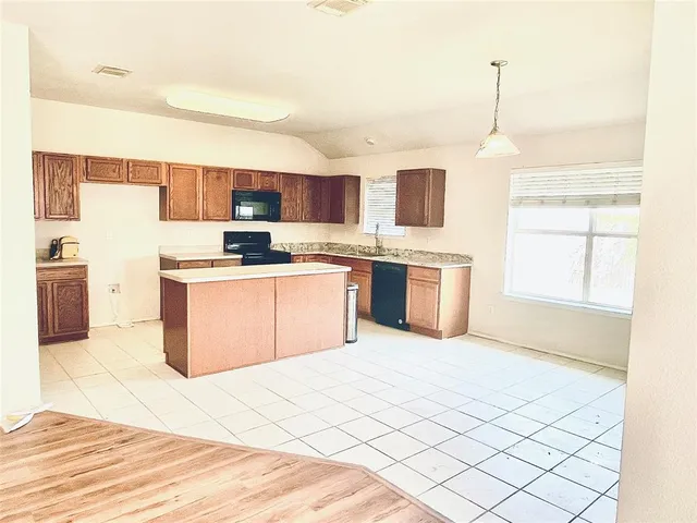 a kitchen with stainless steel appliances kitchen island granite countertop a sink and white cabinets