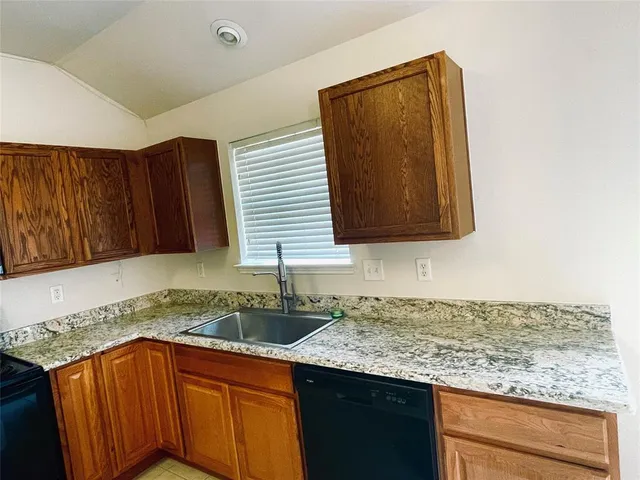 a kitchen with granite countertop a sink and a wooden cabinets