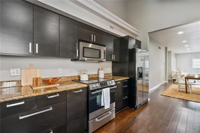 a kitchen with stainless steel appliances granite countertop a stove a sink dishwasher a refrigerator and a microwave