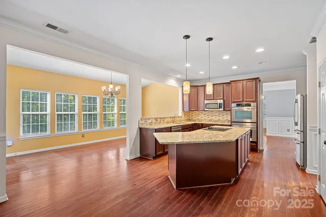 a kitchen with stainless steel appliances granite countertop a stove and a wooden floors