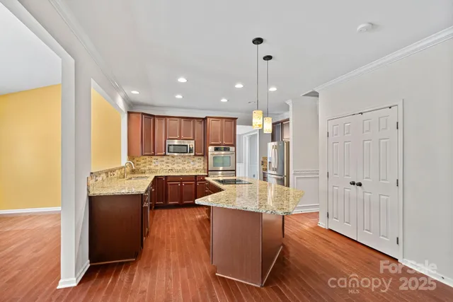 a large kitchen with sink cabinets a counter top space and stainless steel appliances