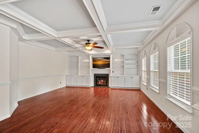 a view of a room with wooden floor fireplace and windows