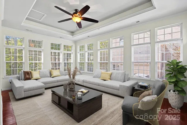 a living room with furniture large windows and a chandelier
