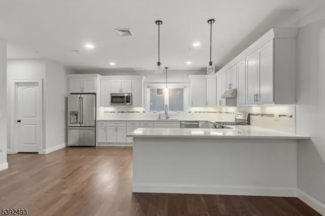 a kitchen with stainless steel appliances granite countertop a sink refrigerator and a wooden cabinets