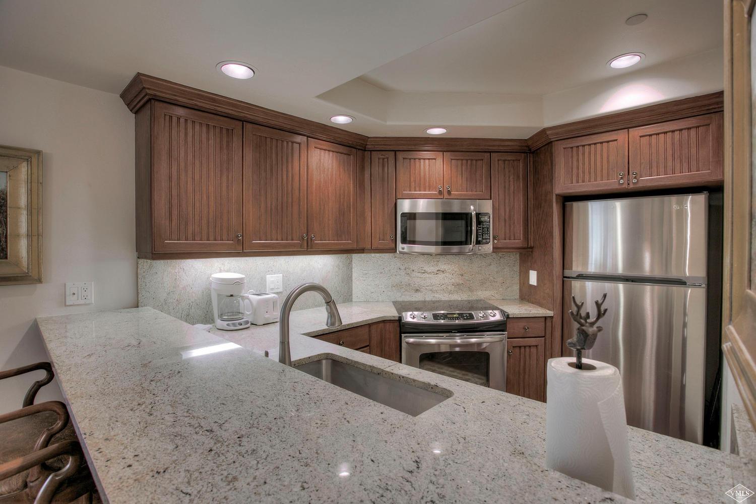 141 Scott Hill Road, Unit 402 Beaver Creek, CO 81620 - Photo 7 of 23 a kitchen with stainless steel appliances granite countertop a refrigerator sink and stove