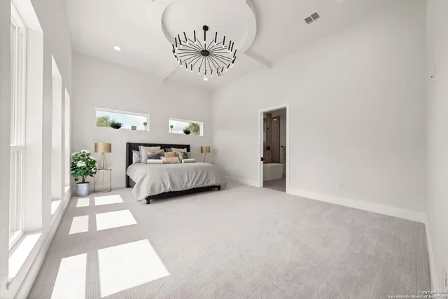 a spacious bedroom with a bed and a chandelier