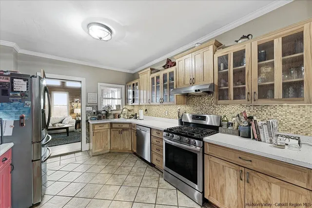 a kitchen with stainless steel appliances granite countertop a stove top oven a sink dishwasher a dining table and chairs with wooden floor