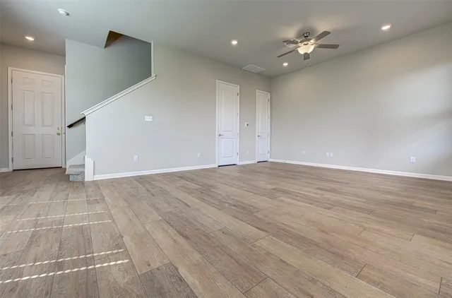 a view of an empty room with a window and wooden floor