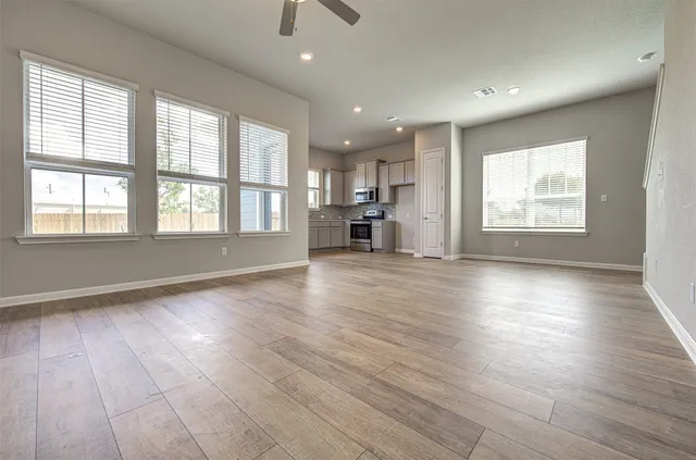 an empty room with wooden floor and windows