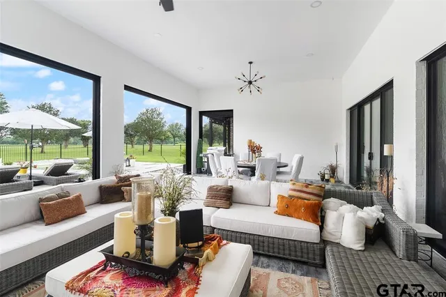 a living room with furniture large windows and wooden floor