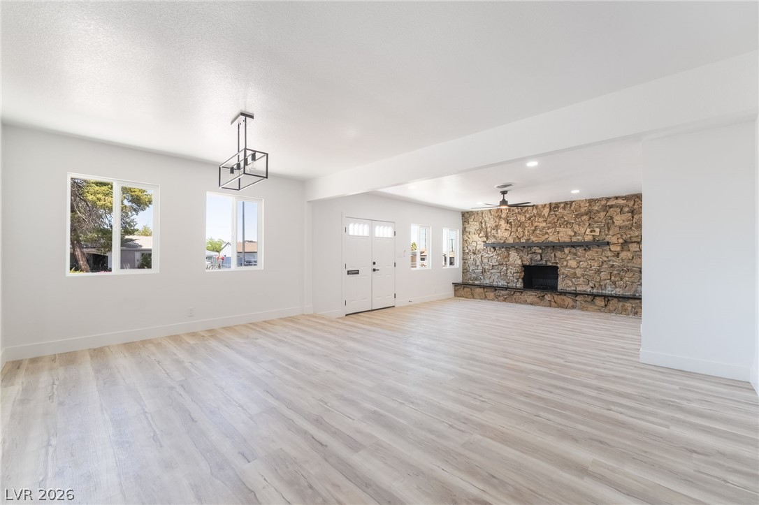 39 Lowery Street Henderson, NV 89015 - Photo 8 of 40 A spacious living area featuring light wood flooring and a stone accent wall with a fireplace.