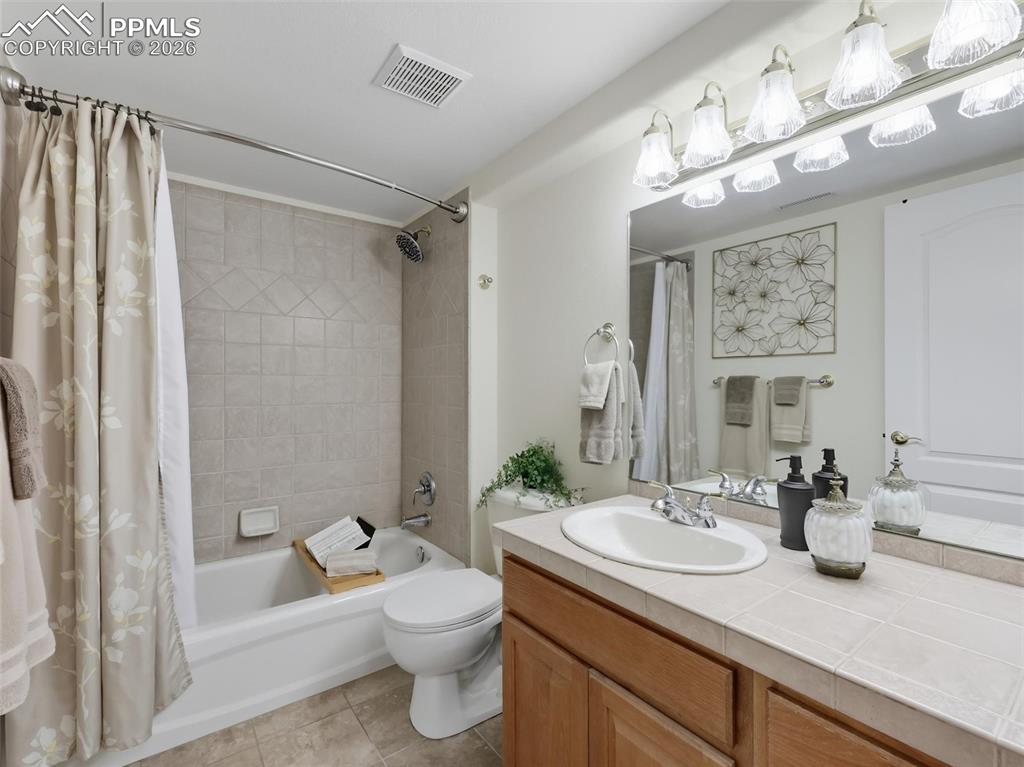 12855 Murphy Road Elbert, CO 80106 - Photo 34 of 50 a bathroom with a granite countertop sink a toilet a mirror a vanity a bathtub and shower