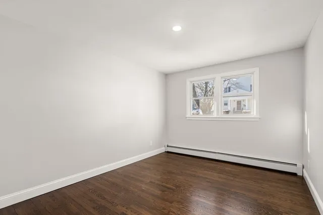 a view of an empty room with wooden floor and window