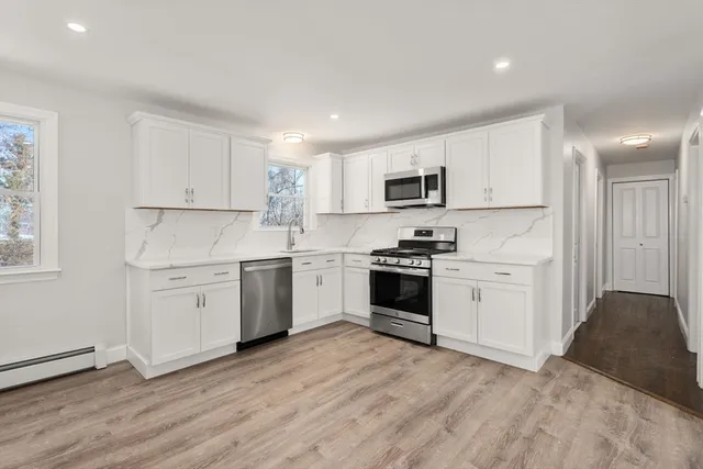 a kitchen with granite countertop white cabinets and stainless steel appliances