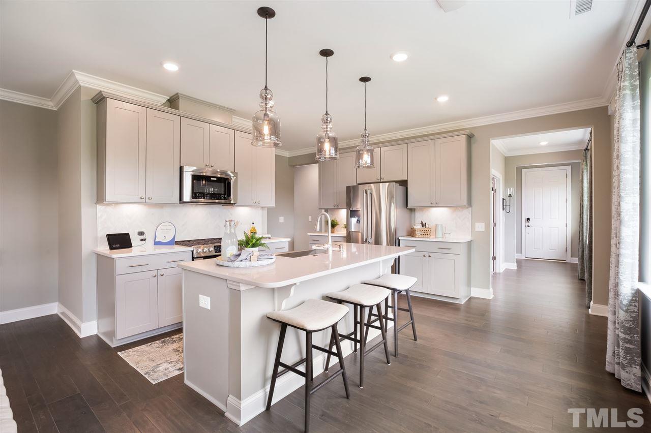 244 Mahogany Run, Unit 192 Raleigh, NC 27610 - Photo 14 of 30 a kitchen with stainless steel appliances kitchen island granite countertop a stove a sink a refrigerator and white cabinets with wooden floor
