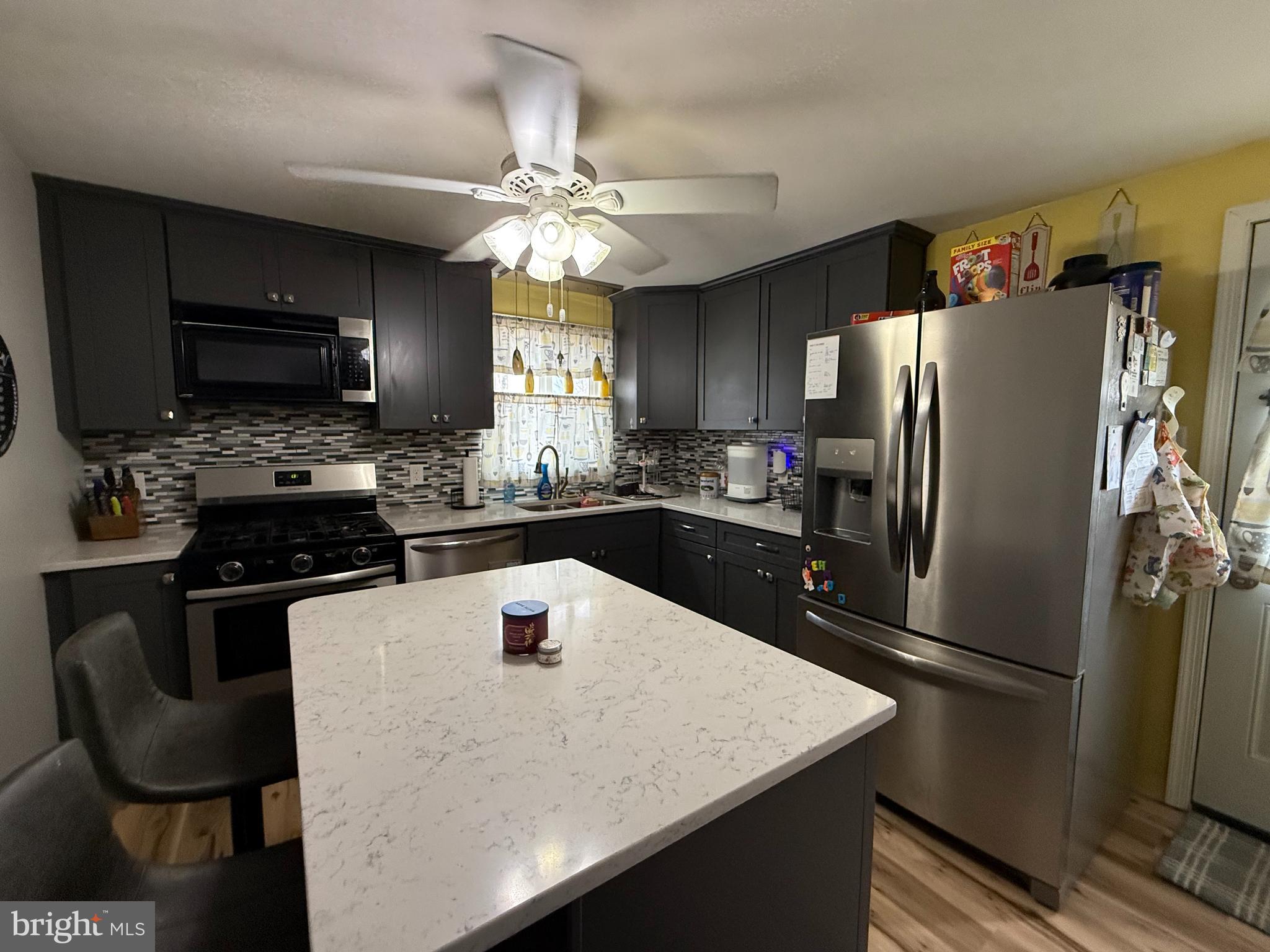 12 North Maple Avenue Ridgely, MD 21660 - Photo 5 of 23 a kitchen with stainless steel appliances granite countertop a sink a stove a refrigerator a kitchen island with chairs and refrigerator
