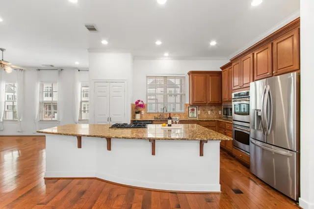 a kitchen with stainless steel appliances granite countertop a sink dishwasher a stove and white cabinets with wooden floor