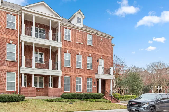 a front view of a building with lot of cars and trees