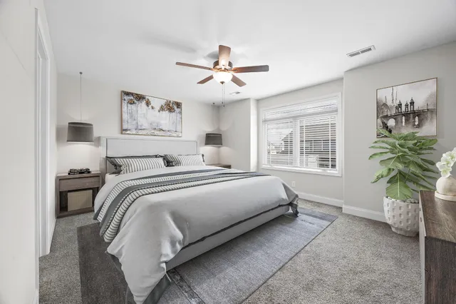 a bedroom with a bed potted plant on the dresser and a window