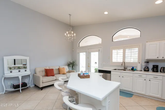 a large white kitchen with a white cabinets and chandelier