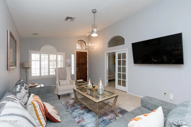 a living room with furniture a flat screen tv and a chandelier